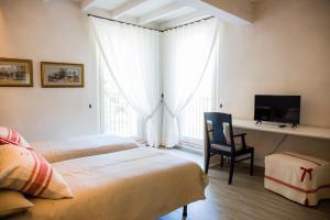 a bedroom with two beds and a desk with a television at Agriturismo Bellarosa in Albinea