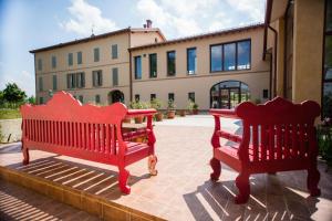 dos bancos rojos sentados frente a un edificio en Agriturismo Bellarosa, en Albinea