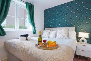 a bed with a tray of fruit and a bottle of wine at Beautiful Apartment - Close to City Centre - Free Parking, Fast Wifi, SmartTV with Sky TV and Netflix by Yoko Property in Northampton
