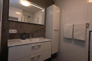 a white bathroom with a sink and a mirror at Spaanse Galeien 79 Cadzand in Cadzand +30 photos