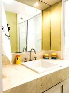 a bathroom with a sink and a large mirror at Charme do Leme in Rio de Janeiro