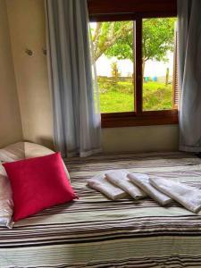 a bed with a red pillow and a window at LOFT.276 - CASA DE CAMPO in Bento Gonçalves