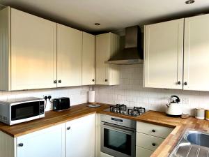 a kitchen with white cabinets and a microwave at Midsummer Cottage Cambridge in Chesterton