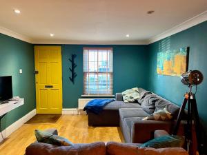 - un salon avec un canapé et une porte jaune dans l'établissement Midsummer Cottage Cambridge, à Chesterton