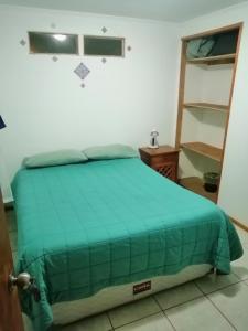 um quarto com uma cama com um edredão verde em Mumus em La Serena