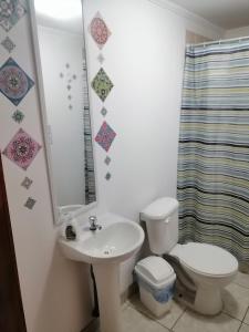 uma casa de banho com um WC, um lavatório e um espelho. em Mumus em La Serena