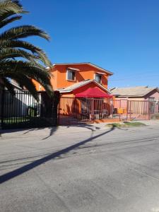 een oranje huis met een hek en een palmboom bij Mumus in La Serena