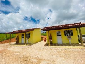 una casa amarilla con un perro de pie junto a ella en Pousada Helena e Heloá en Serra Negra