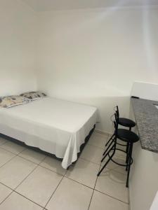 a bedroom with a bed and a chair next to a counter at Pousada Helena e Heloá in Serra Negra