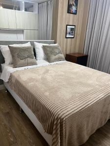 um quarto com uma cama grande com lençóis brancos e almofadas em Flat aconchegante no Jardim Goias em Goiânia
