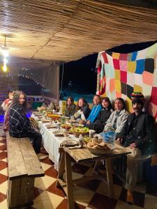 a group of people sitting at a long table at sunny wave taghazout SURF & YOGA in Taghazout