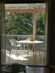 a table and chairs on a porch with a palm tree at Passiflora in Orient Bay
