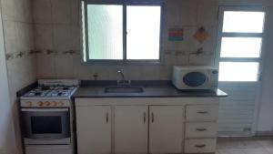 a kitchen with a sink and a stove and a microwave at Alícia in Mar del Plata