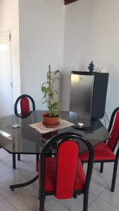 a dining room table with red chairs and a tv at Alícia in Mar del Plata