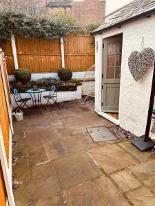 a patio with a table and a building with a fence at NEW Overleigh Cottage, with optional Hot tub in Chester
