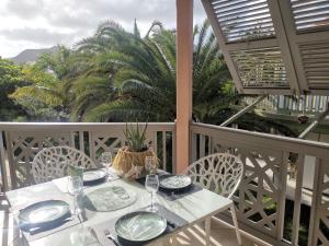- une table avec des assiettes et des verres à vin sur un balcon dans l'établissement Passiflora, à La Baie-Orientale