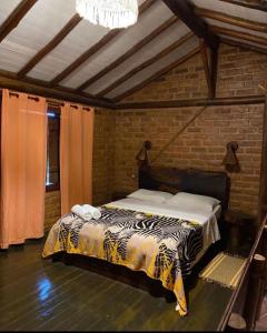 ein Schlafzimmer mit einem Bett in einer Ziegelwand in der Unterkunft Pousada Chalés Vale do Sol in Conceição da Ibitipoca + 52 Fotos