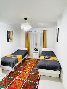 a bedroom with two beds and a rug at Guesthouse GreatHome in Karakol