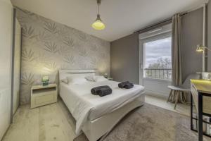 um quarto com uma cama branca e uma janela em Appartement Les Oiseaux em Thionville