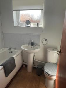 a bathroom with a sink and a toilet and a tub at Chester Cottage in Frodingham +14 photos