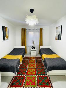 two beds in a room with a rug at Guesthouse GreatHome in Karakol