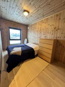 a bedroom with a bed and a wooden wall at Ny hytte, fantastisk utsikt rett ved Vestlia in Geilo