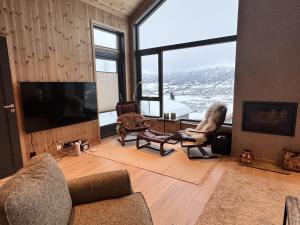 a living room with a tv and a large window at Ny hytte, fantastisk utsikt rett ved Vestlia in Geilo