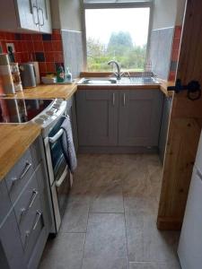 a kitchen with a sink and a stove and a window at 3 Tan Y Coed in Brynkir