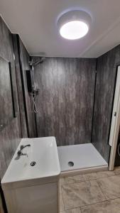 La salle de bains est pourvue d'un lavabo blanc et d'une douche. dans l'établissement 3 Tan Y Coed, à Brynkir