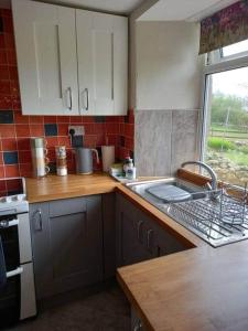 a kitchen with white cabinets and a sink and a window at 3 Tan Y Coed in Brynkir