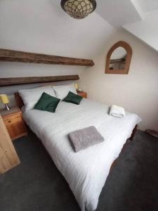 a bedroom with a large white bed with green pillows at 3 Tan Y Coed in Brynkir