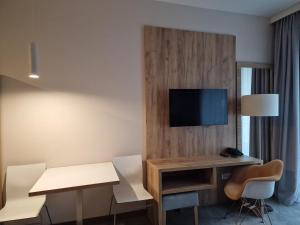 a hotel room with a desk and a tv on a wall at Aparthotel Czarna Góra 239 in Sienna
