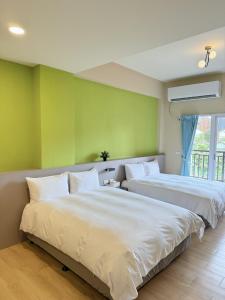 台東市的住宿－台東風巢民宿，绿墙客房内的两张床