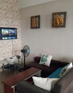 ein Wohnzimmer mit einem Sofa und einem TV in der Unterkunft Alabang Condominium PHC in Manila