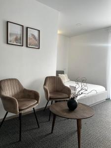 een kamer met 2 stoelen en een tafel en een bed bij Izabelės apartamentai in Palanga