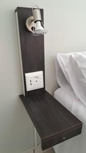 a night stand next to a bed with a light at Chrisserus Guest Rooms in Bloemfontein