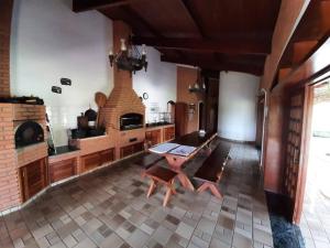 a large kitchen with a table and a brick oven at Linda Chácara em Piracaia SP in Piracaia