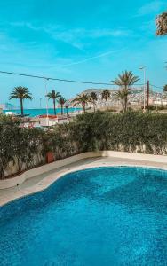 a blue swimming pool with palm trees and the beach at GREEN LAGOON in Calpe