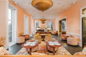 a lobby with tables and chairs and a piano at Hotel Bardo Savannah in Savannah