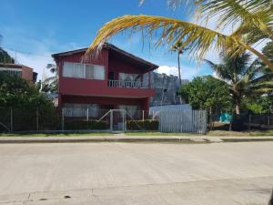 a red house with a palm tree in front of a street at Casa frente al mar hasta 15 personas in Necoclí