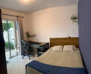 um quarto com uma cama, uma secretária e uma cadeira em Refúgio perto do Mar: Ótima casa a 350m da praia em Pontal do Paraná