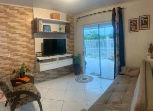 uma sala de estar com um sofá e uma televisão em Refúgio perto do Mar: Ótima casa a 350m da praia em Pontal do Paraná
