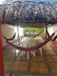 a hammock on a porch with a table and chairs at Casa frente al mar hasta 15 personas in Necoclí