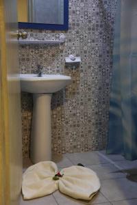 een badkamer met een wastafel en een handdoek op de vloer bij Hotel Amine in Sfax