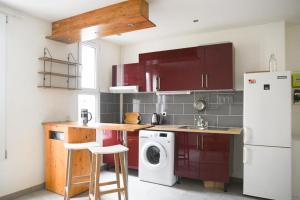 a kitchen with red cabinets and a white refrigerator at Pleasant love cocoon of 30 m in Clichy in Clichy