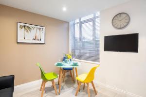 a living room with a table and chairs and a clock at Paradise Suite in Portsmouth