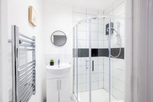 een witte badkamer met een douche en een wastafel bij Paradise Suite in Portsmouth