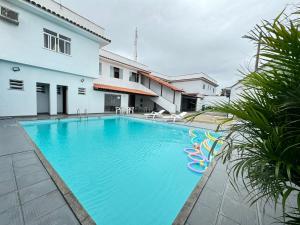 a large blue swimming pool next to a building at Pousada Natalli in Cabo Frio