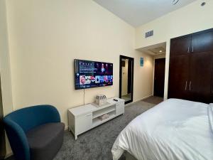 1 dormitorio con 1 cama, 1 silla y TV en Master Room, en Dubái