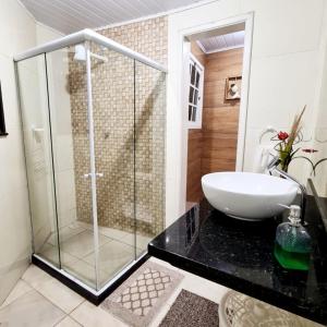a bathroom with a glass shower and a sink at Hospedagem Doce Lar - Casa Manacá in Teresópolis